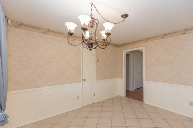 spare room featuring wainscoting, wallpapered walls, a chandelier, and light tile patterned floors