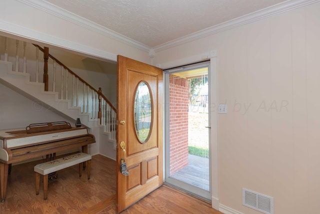 foyer entrance featuring light wood finished floors, visible vents, stairs, and crown molding