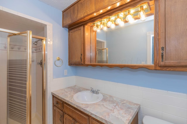 bathroom featuring tile walls, toilet, vanity, and a stall shower