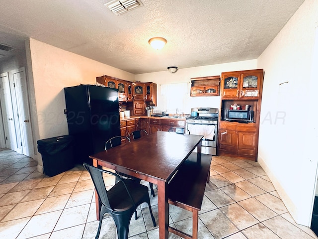 dining room with light tile patterned flooring, a textured ceiling, and visible vents