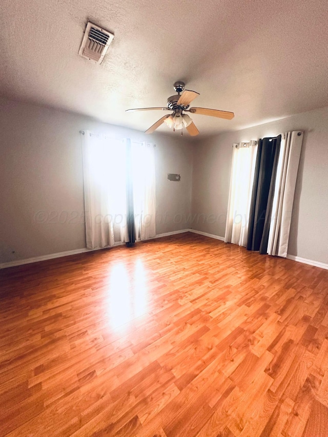 empty room featuring baseboards, ceiling fan, visible vents, and light wood-style flooring