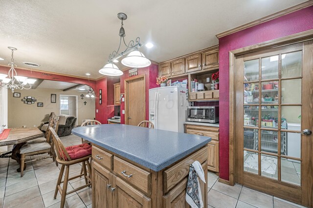 7216 Gainsborough Rd, Amarillo, TX 79106 - kitchen with stainless steel microwave, white refrigerator with ice dispenser, light tile patterned flooring, a center island, and a chandelier
