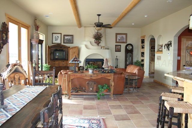 tiled dining space with a large fireplace, ceiling fan, and beam ceiling