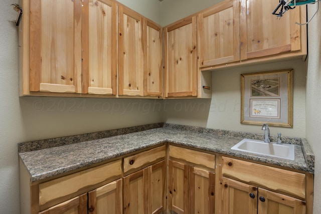 kitchen with light brown cabinets, dark stone countertops, and sink