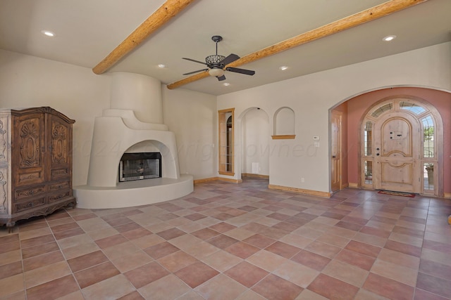 unfurnished living room featuring beamed ceiling, ceiling fan, a large fireplace, and light tile patterned floors