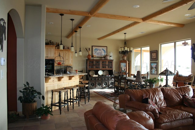 living room with ceiling fan with notable chandelier, beam ceiling, and light tile patterned floors