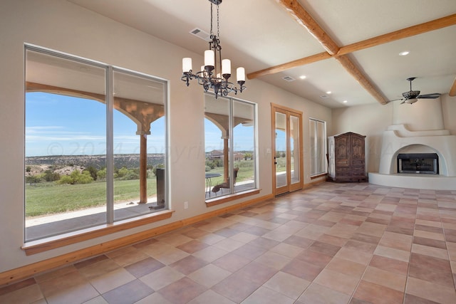 unfurnished living room with a fireplace, beamed ceiling, a healthy amount of sunlight, and ceiling fan with notable chandelier