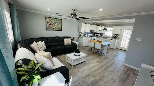 living room featuring baseboards, ornamental molding, recessed lighting, and light wood-style floors