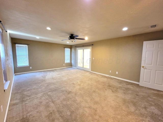 spare room with baseboards, visible vents, a textured ceiling, and carpet