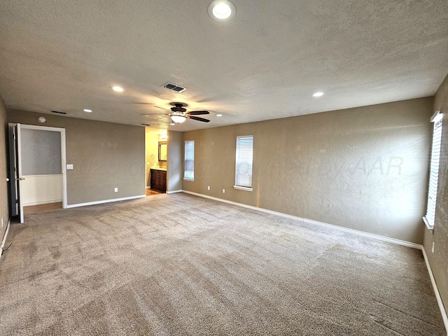 empty room featuring visible vents, baseboards, carpet floors, a textured wall, and a textured ceiling