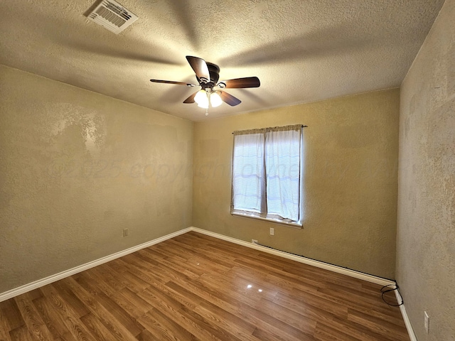 spare room featuring wood finished floors, visible vents, and baseboards