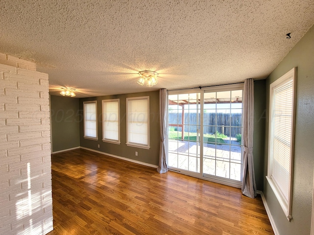 empty room featuring baseboards, a textured ceiling, and wood finished floors