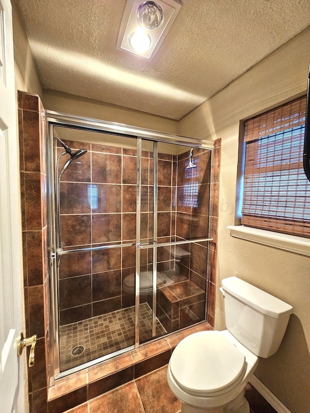 bathroom featuring toilet, a stall shower, tile patterned flooring, and a textured ceiling