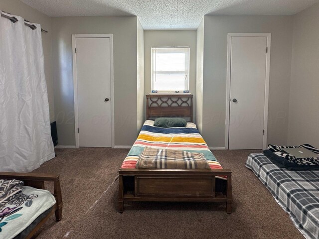 bedroom with dark carpet and a textured ceiling