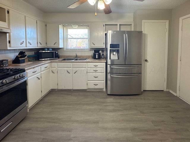 kitchen featuring sink, white cabinets, light hardwood / wood-style floors, and appliances with stainless steel finishes