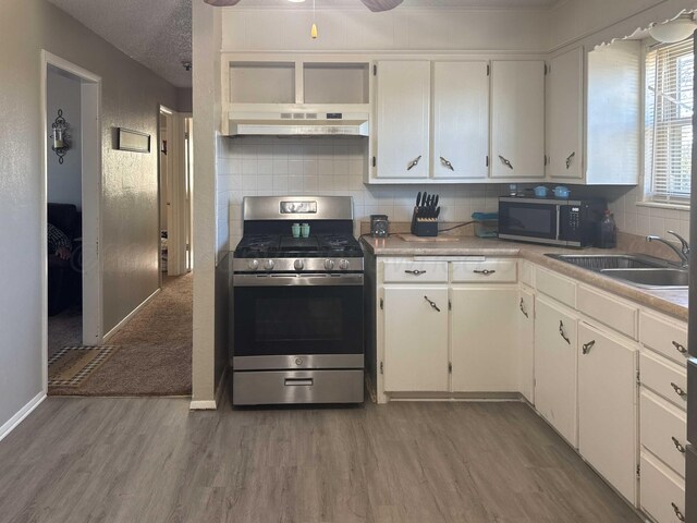 kitchen with a textured ceiling, stainless steel appliances, sink, hardwood / wood-style floors, and white cabinetry