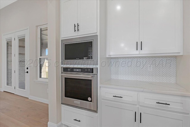 5805 Sheridan St, Amarillo, TX 79119 - kitchen with stainless steel appliances, light wood-style floors, tasteful backsplash, white cabinets, and light stone counters