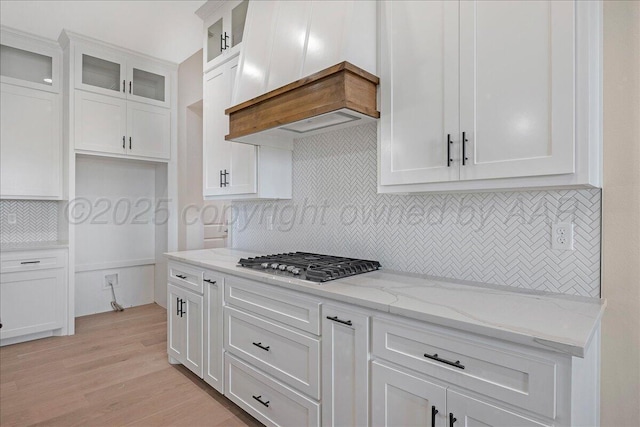 5805 Sheridan St, Amarillo, TX 79119 - kitchen with stainless steel gas stovetop, backsplash, white cabinets, light stone counters, and glass insert cabinets