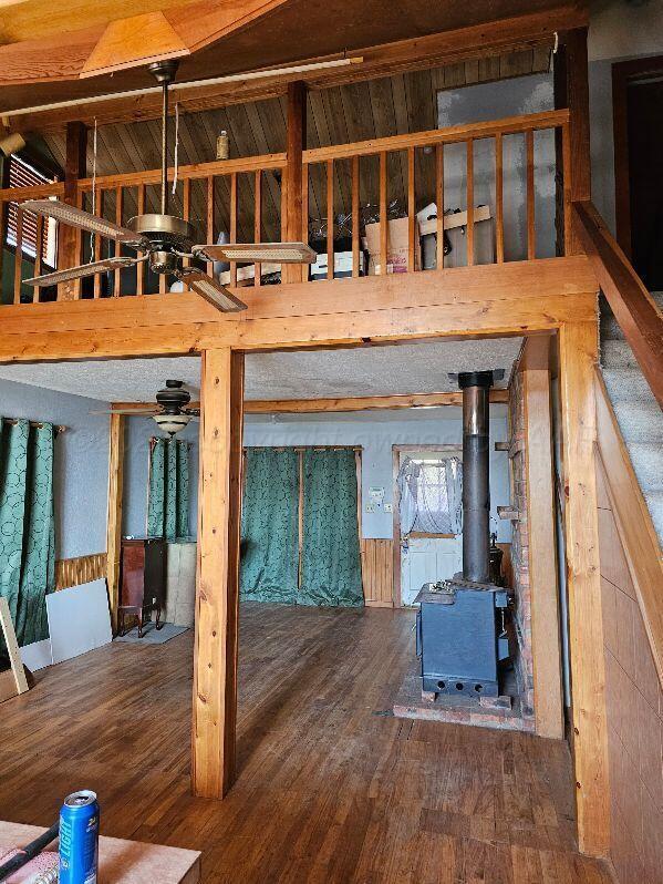 interior space with hardwood / wood-style flooring, ceiling fan, and a wood stove