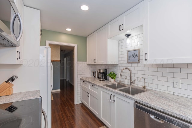 kitchen featuring appliances with stainless steel finishes, a sink, white cabinets, dark wood-style flooring, and recessed lighting