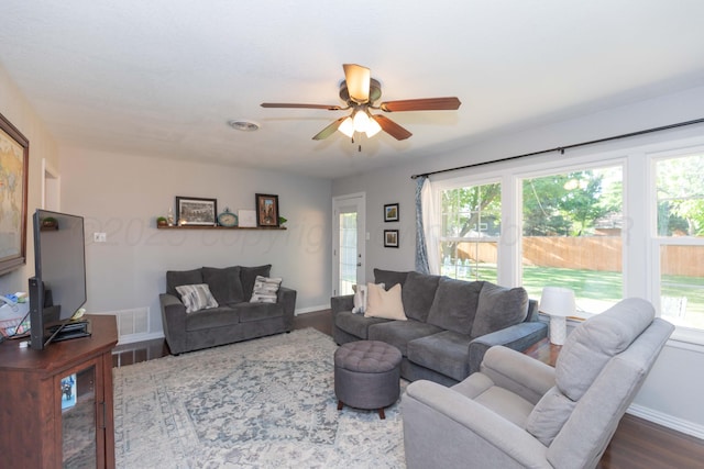 living area featuring ceiling fan, dark wood-type flooring, healthy amount of natural light, and baseboards