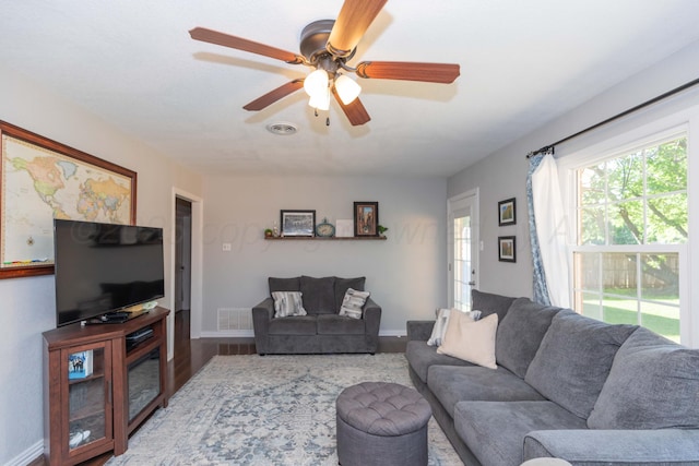 living room featuring ceiling fan, baseboards, and wood finished floors