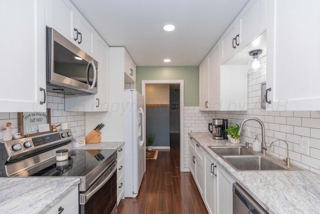 kitchen featuring appliances with stainless steel finishes, a sink, white cabinetry, dark wood-style floors, and recessed lighting