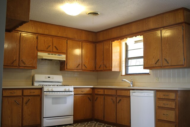708 N Arizona St, Shamrock, TX 79079 - kitchen featuring white appliances, under cabinet range hood, brown cabinetry, light countertops, and a textured ceiling