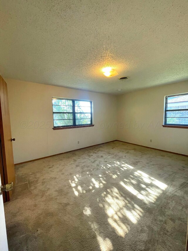 708 N Arizona St, Shamrock, TX 79079 - carpeted empty room featuring plenty of natural light and a textured ceiling