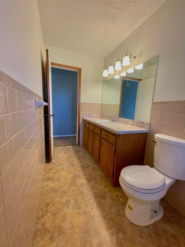 708 N Arizona St, Shamrock, TX 79079 - bathroom with tile walls, wainscoting, a textured ceiling, and vanity