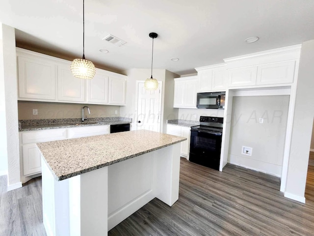 kitchen featuring light stone countertops, white cabinetry, a center island, and black appliances