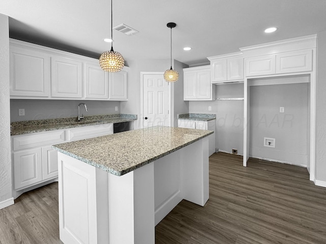 kitchen featuring white cabinetry, a center island, light stone countertops, hardwood / wood-style floors, and decorative light fixtures