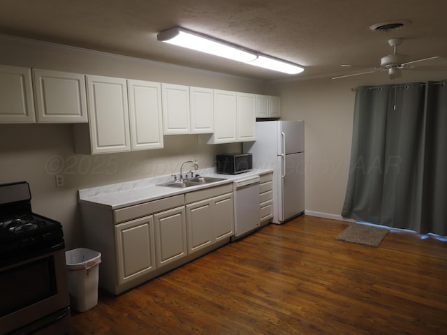 kitchen with a sink, light countertops, white cabinets, dark wood-style floors, and white appliances