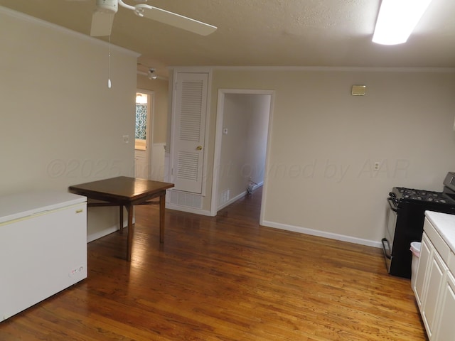 kitchen with ceiling fan, white refrigerator, stainless steel range with gas stovetop, light wood finished floors, and ornamental molding