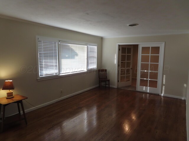 unfurnished room with baseboards, visible vents, french doors, and wood finished floors