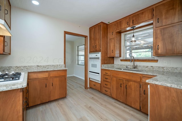 kitchen featuring hanging light fixtures, stainless steel gas cooktop, sink, and light hardwood / wood-style flooring