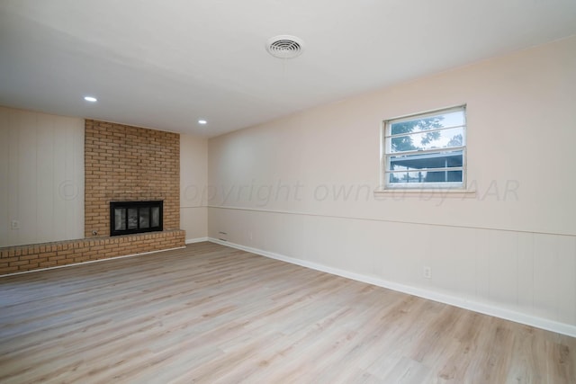 unfurnished living room featuring light wood-type flooring and a brick fireplace