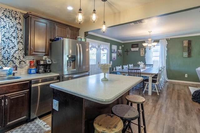 kitchen featuring stainless steel appliances, wood-type flooring, a breakfast bar area, dark brown cabinets, and a kitchen island