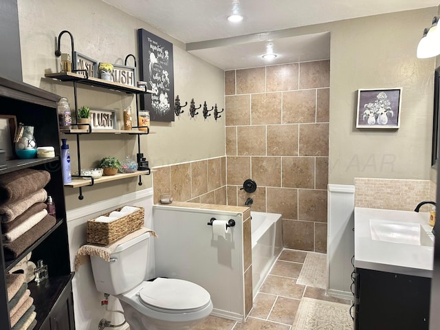 bathroom with a tub to relax in, tile patterned floors, toilet, vanity, and tile walls