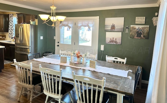 dining area featuring sink, hardwood / wood-style flooring, crown molding, and a notable chandelier