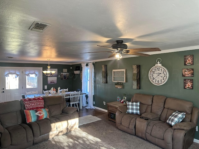 carpeted living room featuring ceiling fan with notable chandelier and crown molding