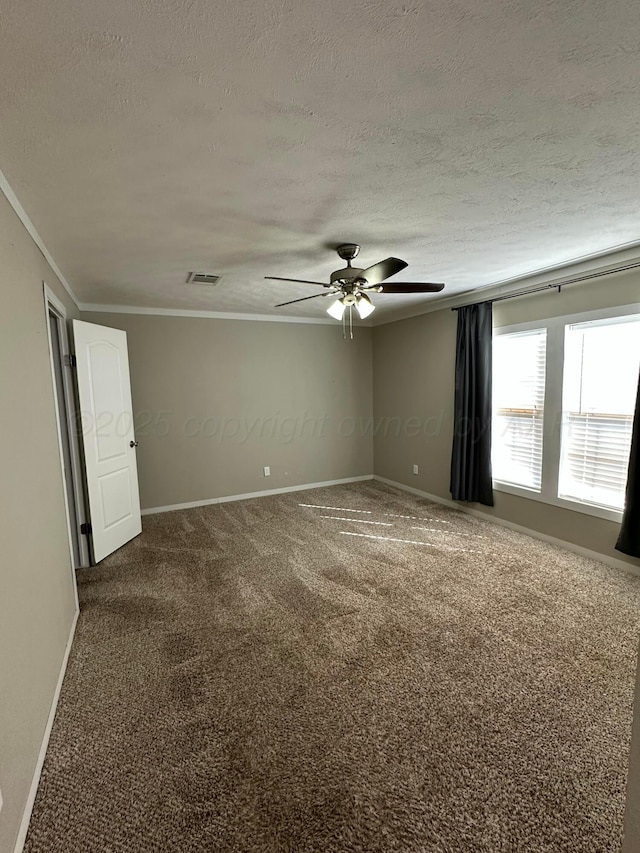 carpeted empty room featuring baseboards, a textured ceiling, visible vents, and crown molding