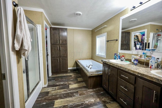 full bath featuring a garden tub, crown molding, double vanity, a sink, and wood finished floors