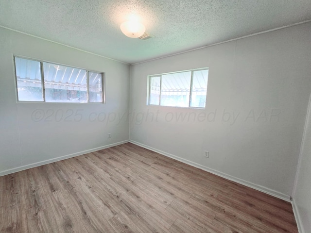 unfurnished room featuring a textured ceiling, wood finished floors, and baseboards