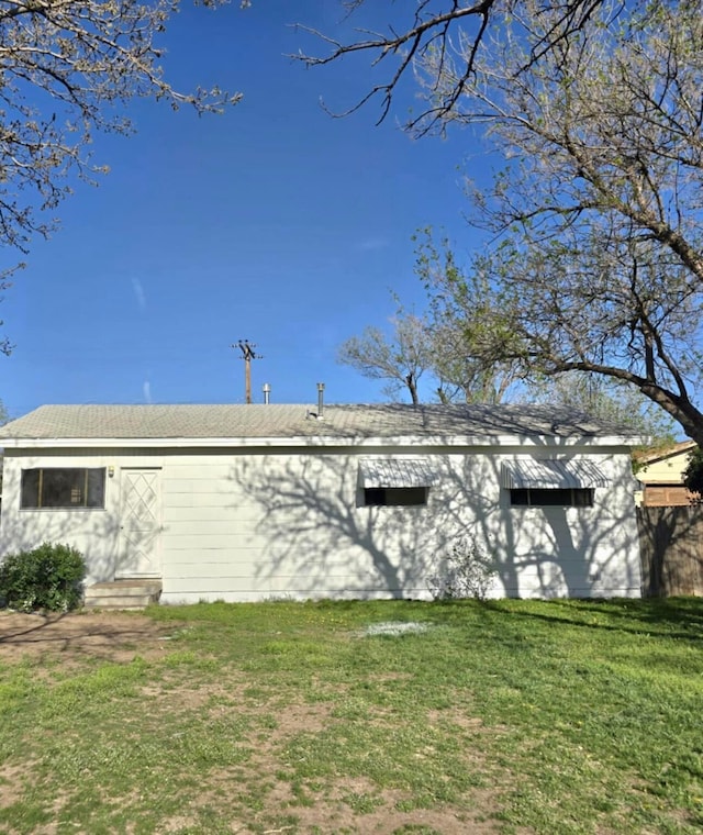 back of property featuring entry steps and a lawn