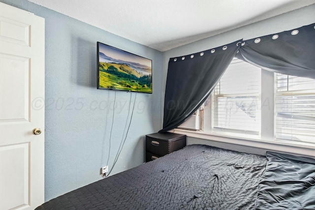 bedroom featuring cooling unit and a textured wall