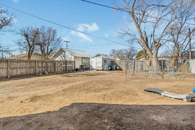 view of yard featuring a shed, a fenced backyard, and an outbuilding