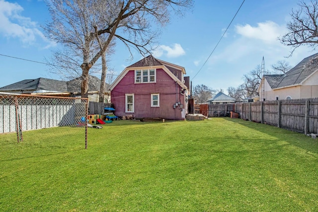 rear view of property with a fenced backyard and a lawn