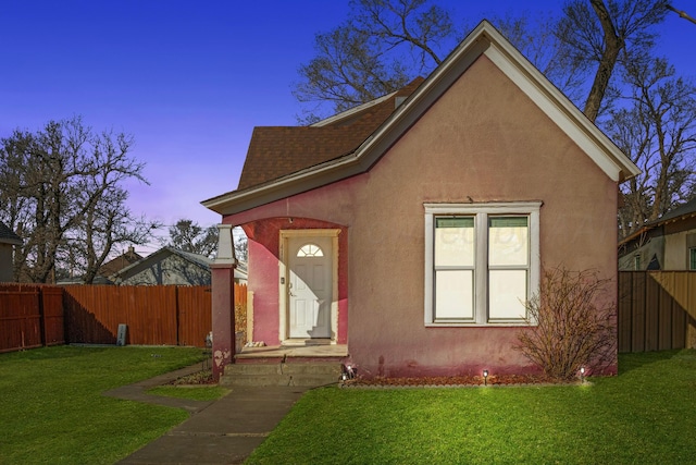 view of front of home with a lawn, fence, and stucco siding