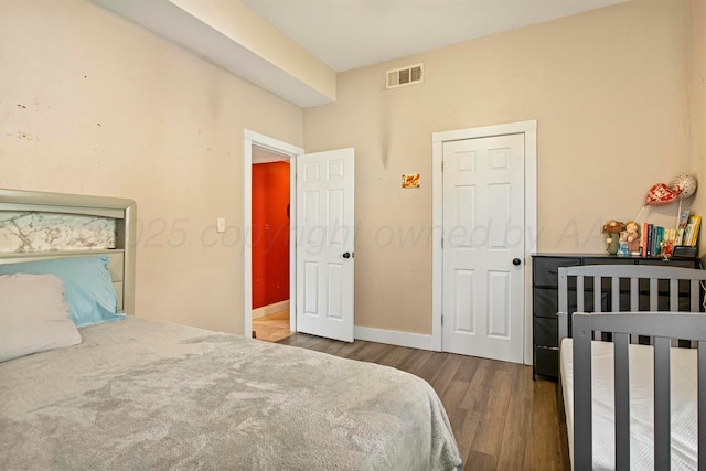 bedroom with wood finished floors, visible vents, and baseboards